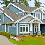 Roof Replacement Milwaukee WI Blue home with grey roofing and a lawn with bright green grass